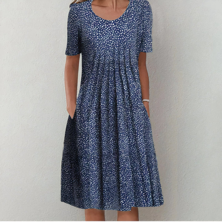Navy blue dress with small white dots in a studio setting.