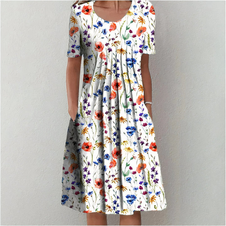 White dress with vibrant floral pattern, featuring red, blue, orange, and yellow flowers in a studio setting.