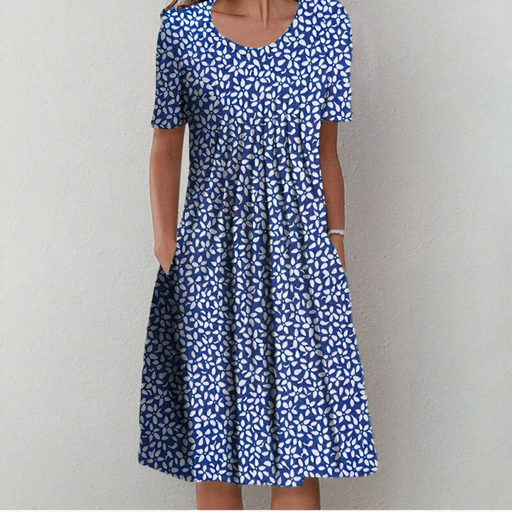Blue dress with a white leafy pattern in a studio setting.
