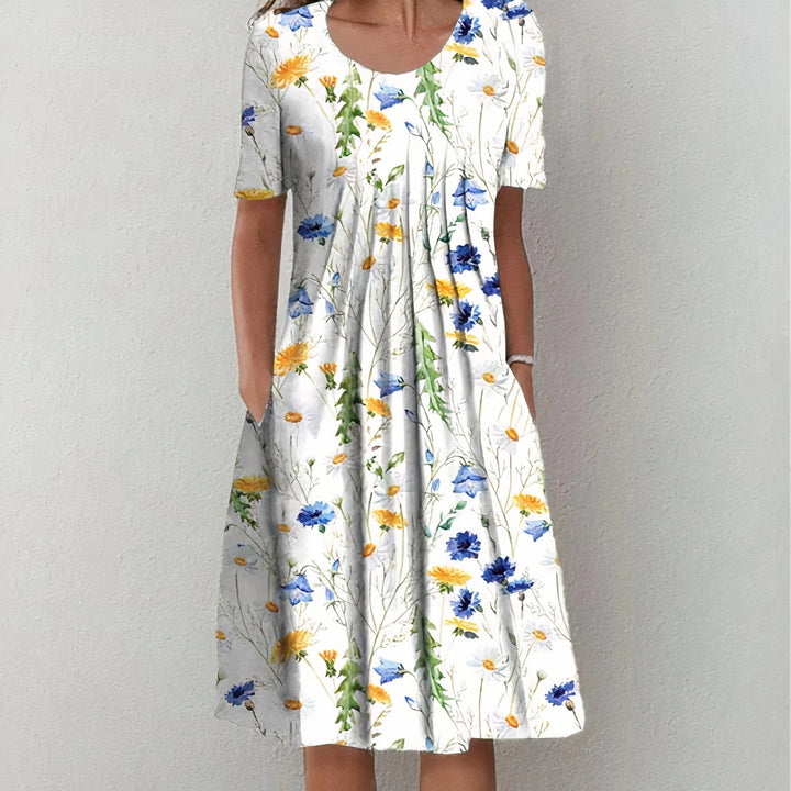 White dress with blue and yellow floral pattern in a studio setting.
