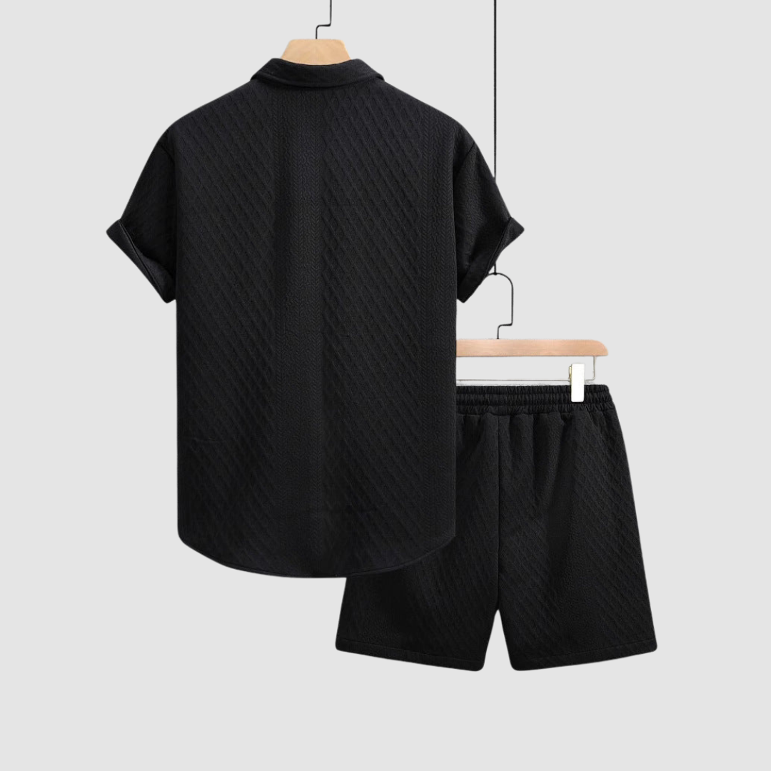 Back view of black short-sleeve shirt and shorts on hangers against a light gray background.