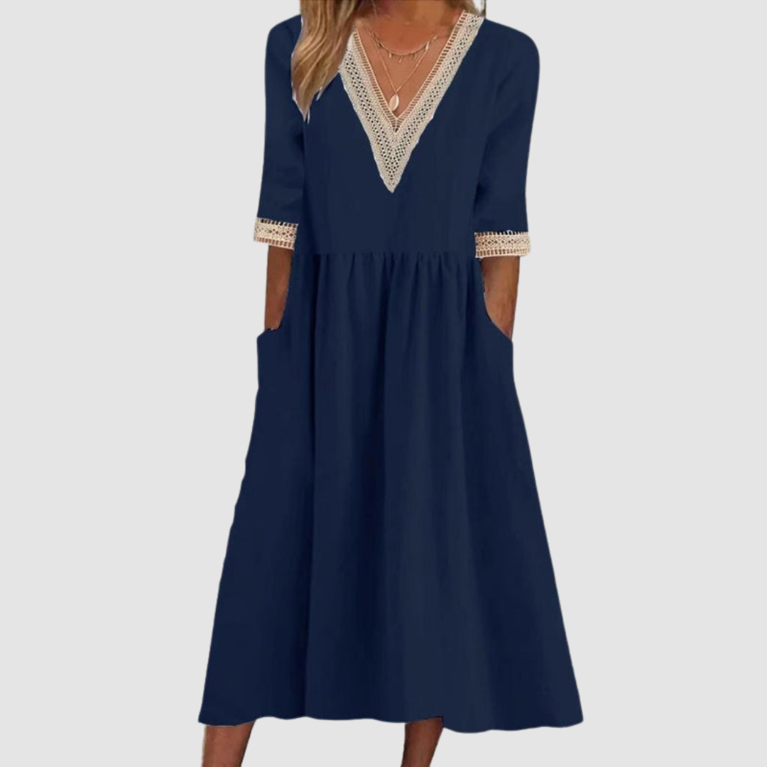 Navy mid-length dress with crochet trim neckline and sleeves, styled in a studio on a light gray background.
