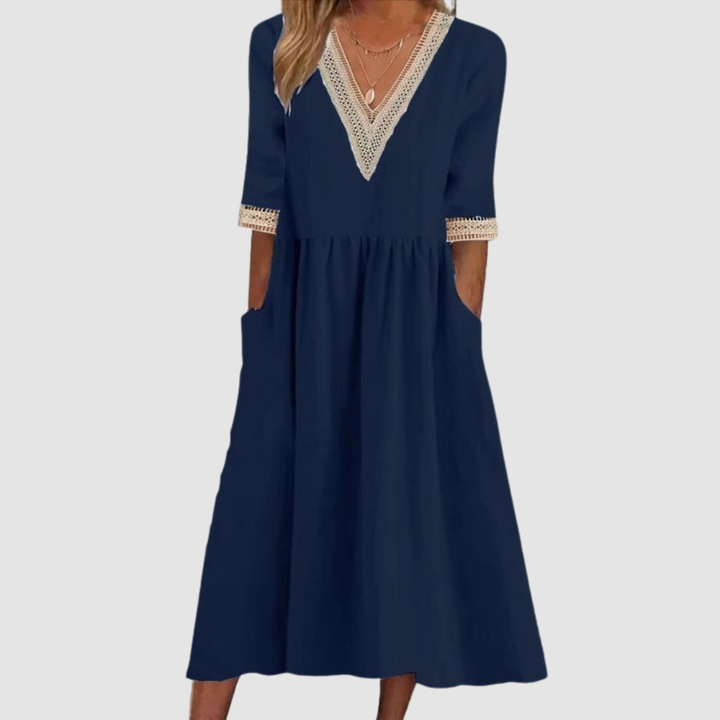 Navy mid-length dress with crochet trim neckline and sleeves, styled in a studio on a light gray background.