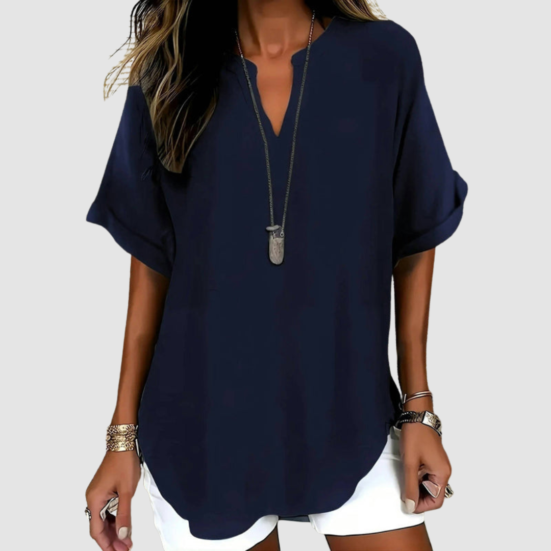 Elegant navy blouse with rolled sleeves and a deep V-neck, paired with white shorts, set in a light gray studio background.