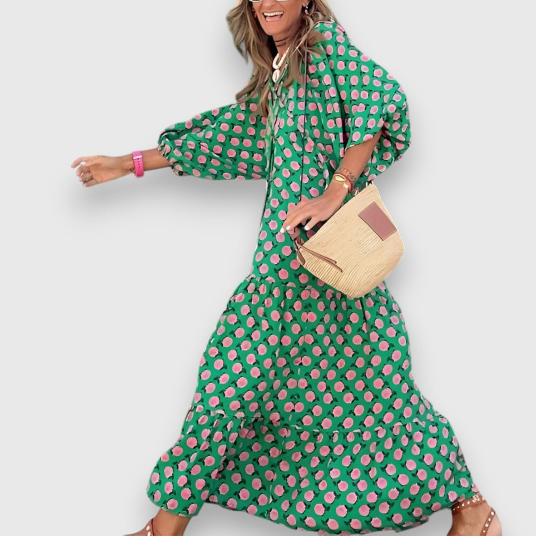 Side profile of woman in green dress with pink floral pattern, smiling and holding woven bag, on plain background.