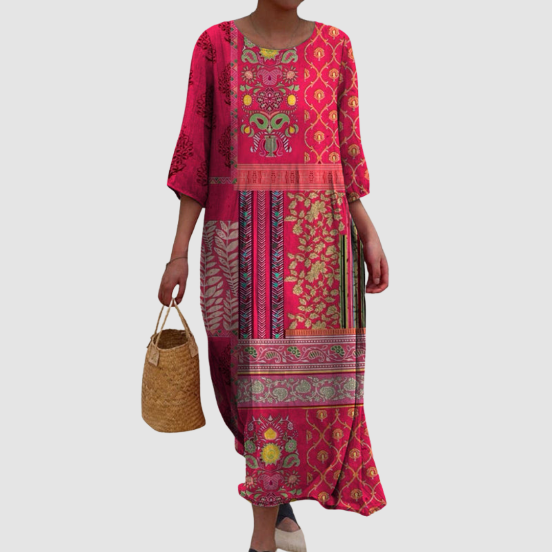 Colorful, patterned summer dress with a relaxed fit, featuring floral and geometric designs. Model holds a woven bag, set against a plain background.