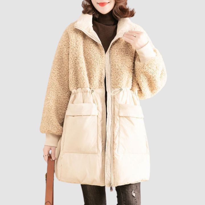 Beige winter coat with textured upper and smooth lower, worn by model holding a bag in a neutral setting.