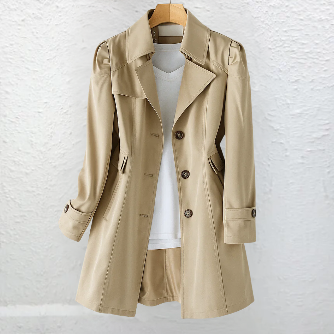 Light brown coat on a hanger, positioned before a textured white wall.