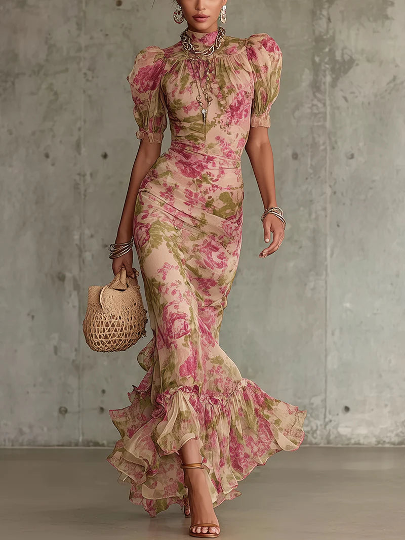 Woman in a floral vintage maxi dress holding a woven bag, standing against a concrete wall.