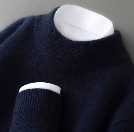 Close-up of a soft, navy blue sweater with a ribbed turtleneck and cuff on a dark background.