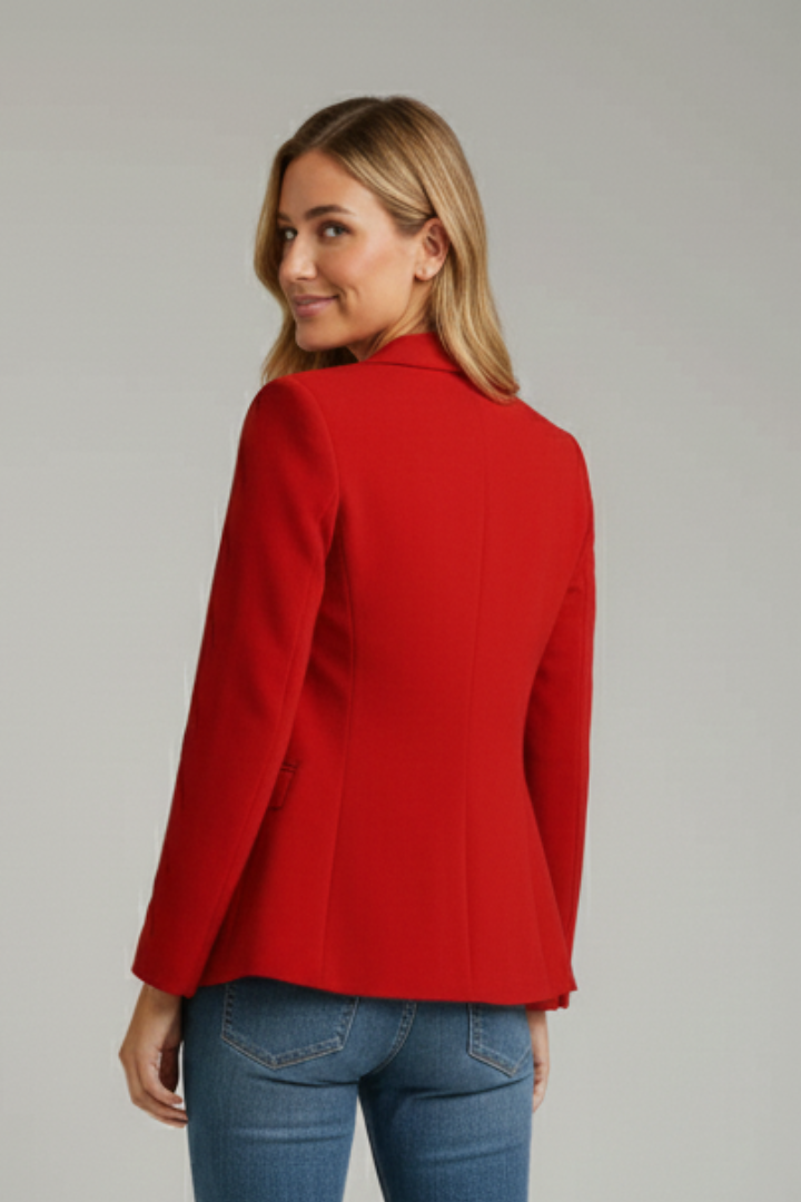 Rear view of model in red blazer and jeans, plain background.