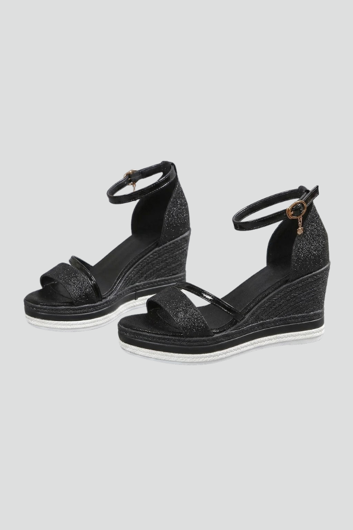 Black orthopaedic cushioned sandals with wedge heels and ankle straps in a studio setting.