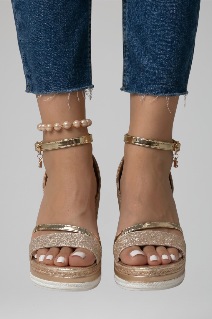 Gold glittery cushioned sandals on feet, paired with blue denim jeans in a studio setting.