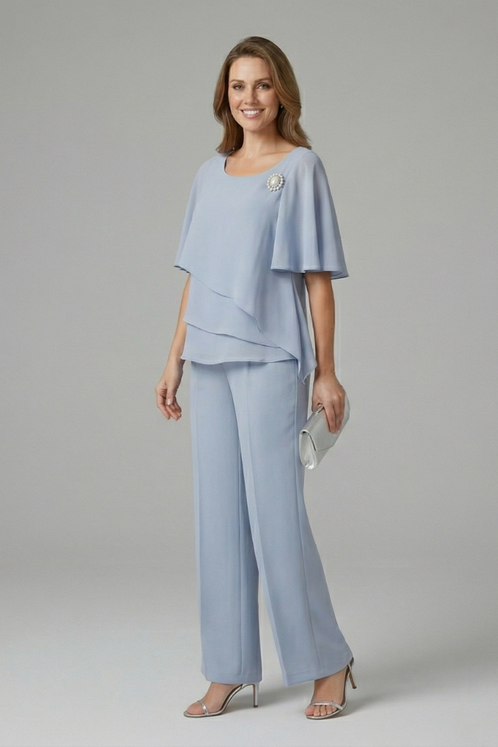 Side view of model in light blue top and trousers set, holding a clutch, in a studio environment.