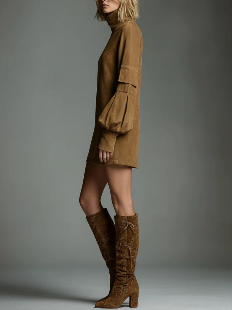 Profile view of model in tan vintage turtleneck mini dress with balloon sleeves, paired with tall textured boots, studio setting.