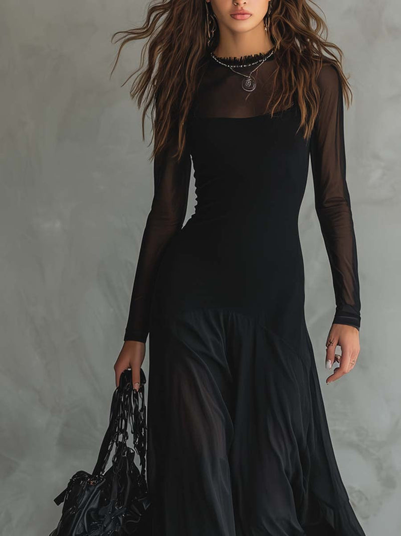 Close-up of a black flowy dress with sheer long sleeves, worn by a woman holding a black bag in a studio setting.