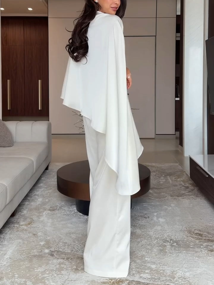 Back view of woman in white two-piece set showing draped design in a modern living room.
