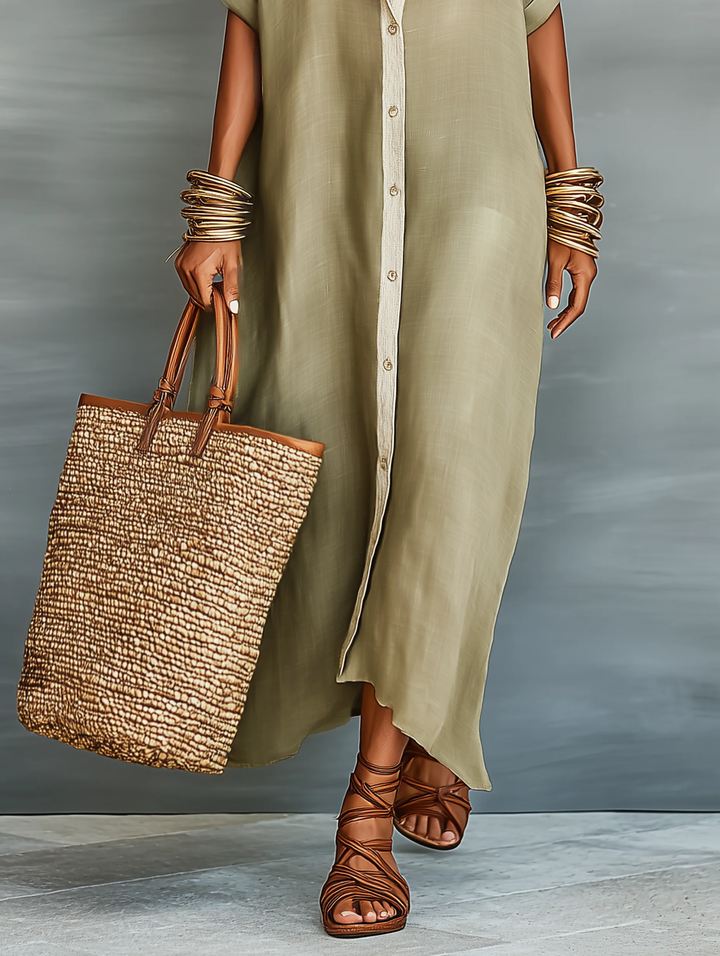 Lower view of olive green maxi dress displaying button detail, styled with layered bracelets, a woven tote bag, and brown gladiator sandals. Studio background.
