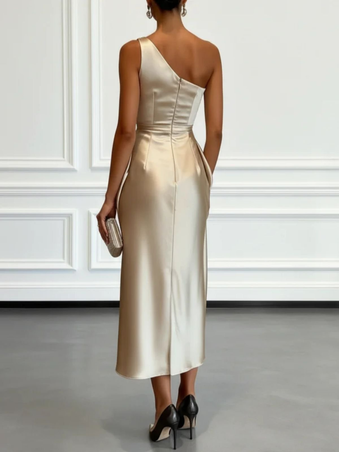 Back view of champagne one-shoulder midi dress with sleek silhouette in a simple room.