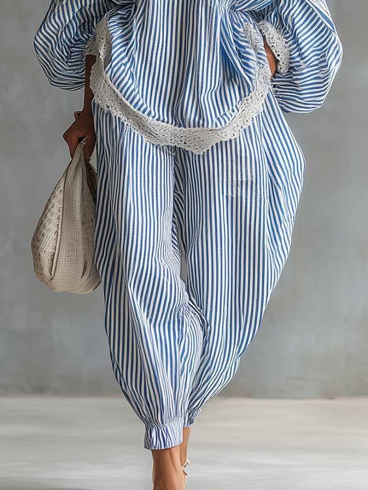 Close-up of blue and white striped pants with lace trim, holding a woven bag, against a gray studio background.