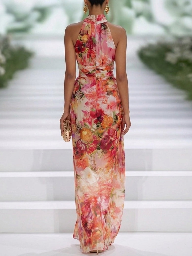 Rear view of a floral sleeveless maxi dress on a model, showcasing the vibrant print on a runway with a white staircase.