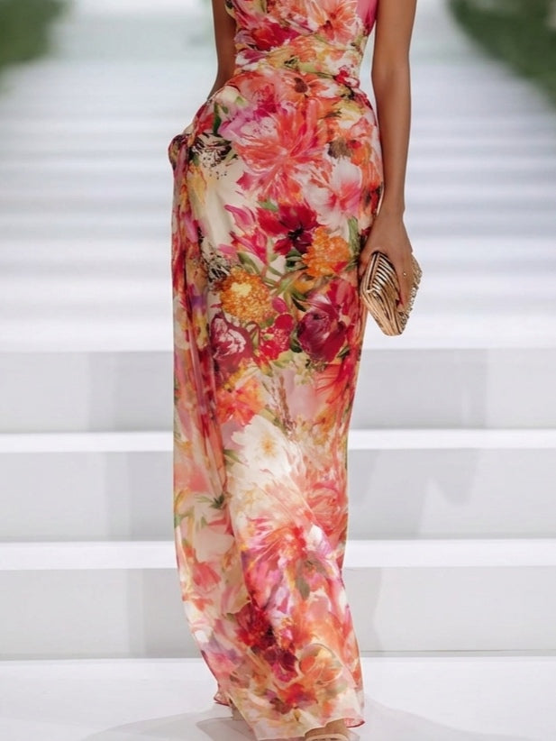 Lower view of floral sleeveless maxi dress, highlighting vivid patterns as a model stands on white staircase runway.