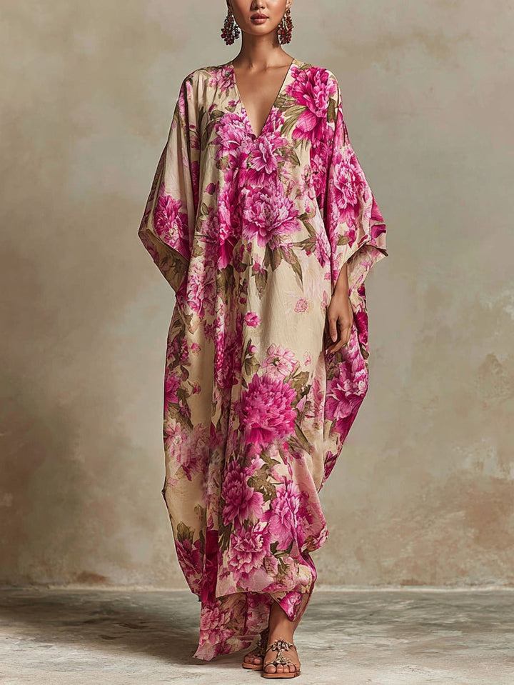 Elegant maxi dress with vibrant pink floral pattern, flowing sleeves, and v-neck in neutral, textured indoor setting.