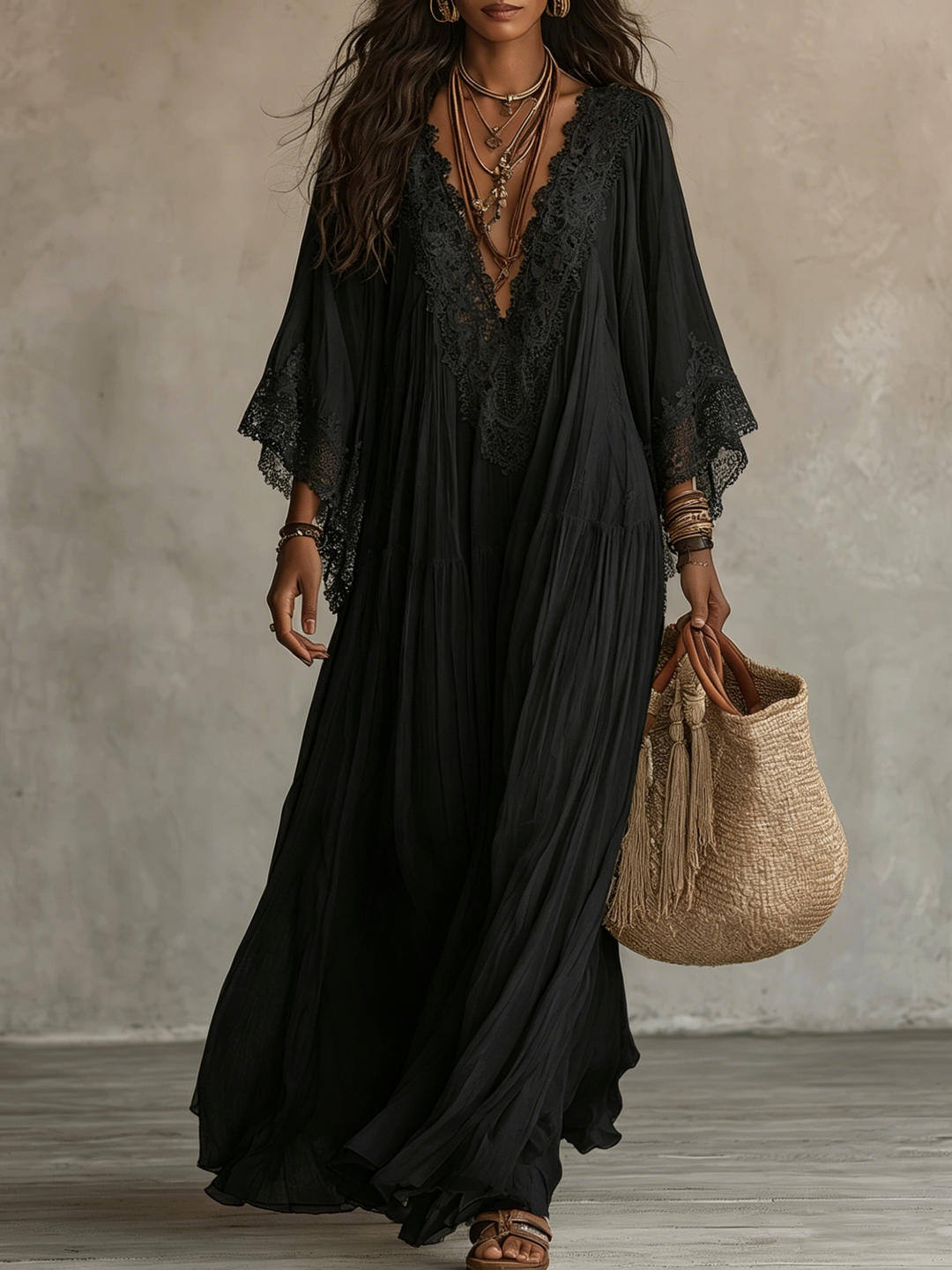 Black batwing sleeve maxi dress with lace detailing worn by a model carrying a tassel-adorned straw bag in a neutral indoor setting.
