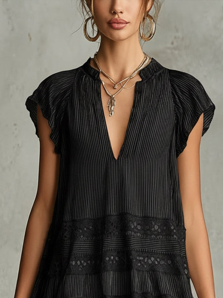 Close-up of upper portion of black striped chiffon dress with lace trim, modeled in a studio.