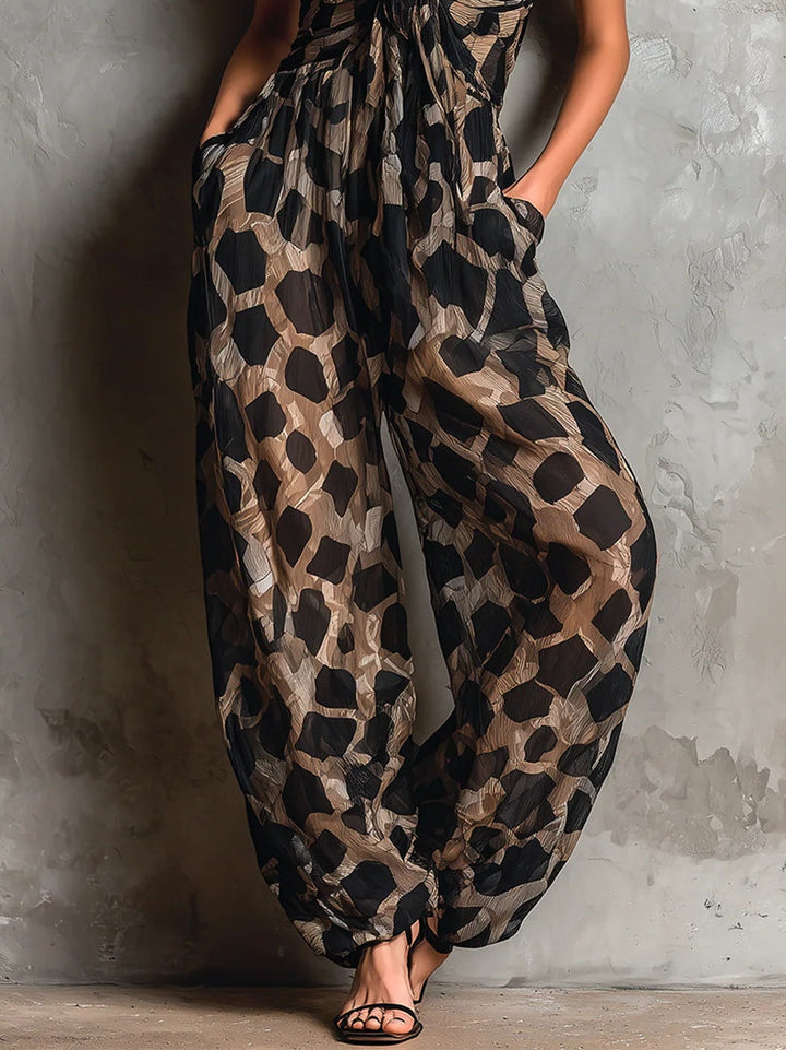 Lower view of black animal print halter-neck chiffon jumpsuit highlighting wide legs and sandals in studio.