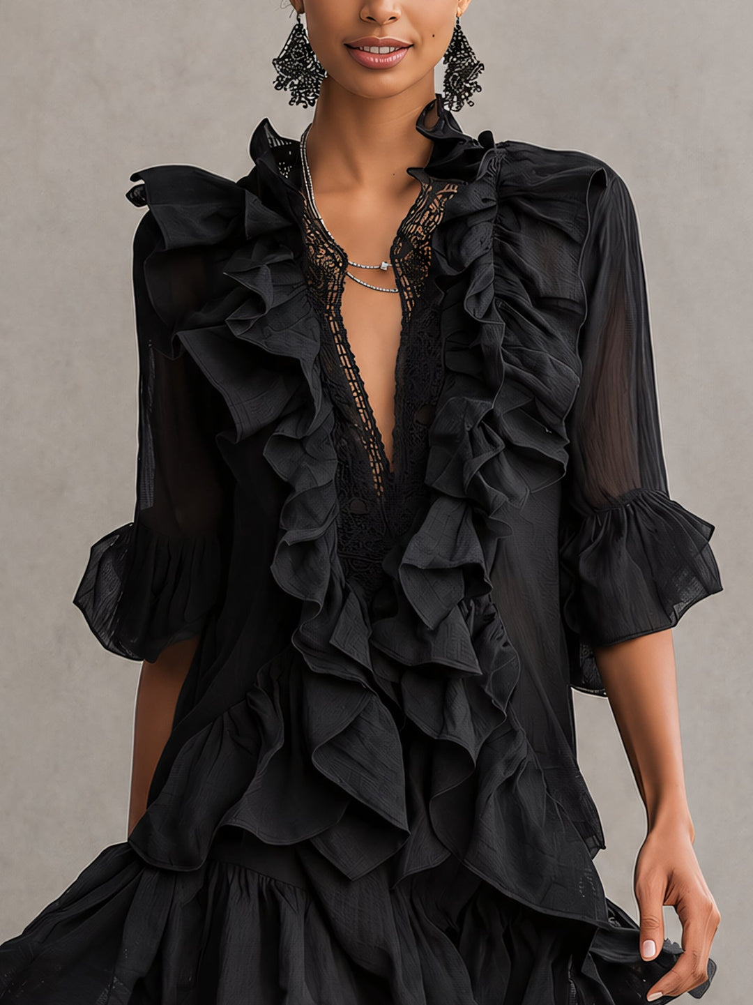 Close-up of a black mini dress with cascading ruffles and lace neckline, worn by a woman in a studio setting.