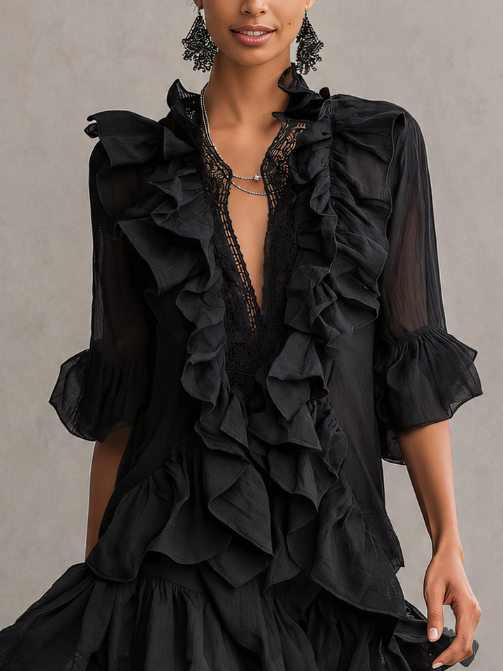 Close-up of a black mini dress with cascading ruffles and lace neckline, worn by a woman in a studio setting.