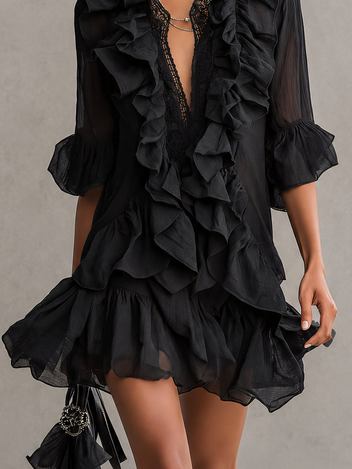 Black ruffled mini dress with lace detail worn by a woman, shown mid-thigh in a studio setting.