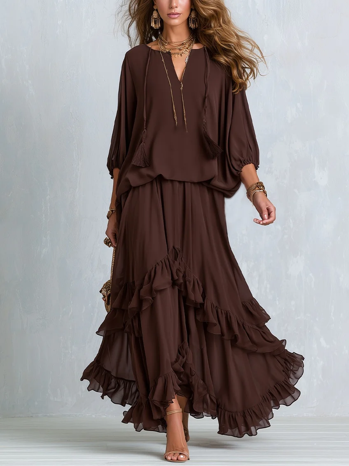 Brown chiffon top with tassel drawstring and ruffled layered skirt, worn by a woman, against a light backdrop.