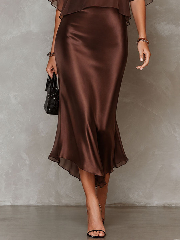 Front view of a brown midi dress with a delicate overlay in a studio. Model wears open-toe heels.