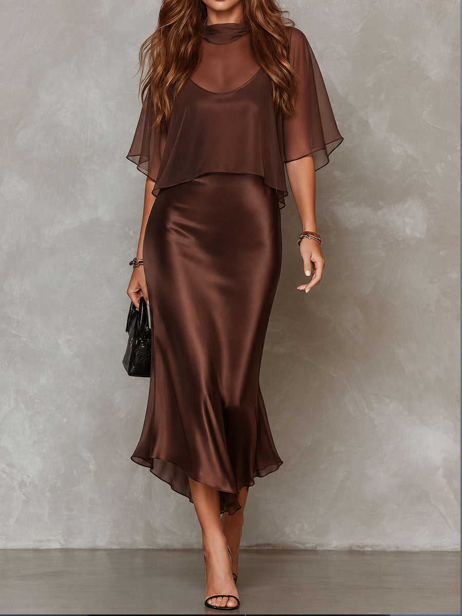 Brown midi dress with a flowy overlay in a studio setting. Model wears strappy heels.