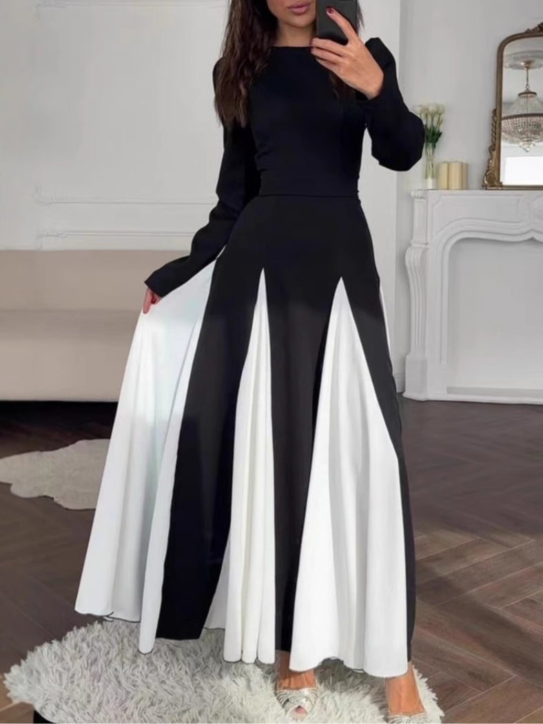 Chic colorblock dress featuring black top and white skirt details, modeled indoors with elegant decor.