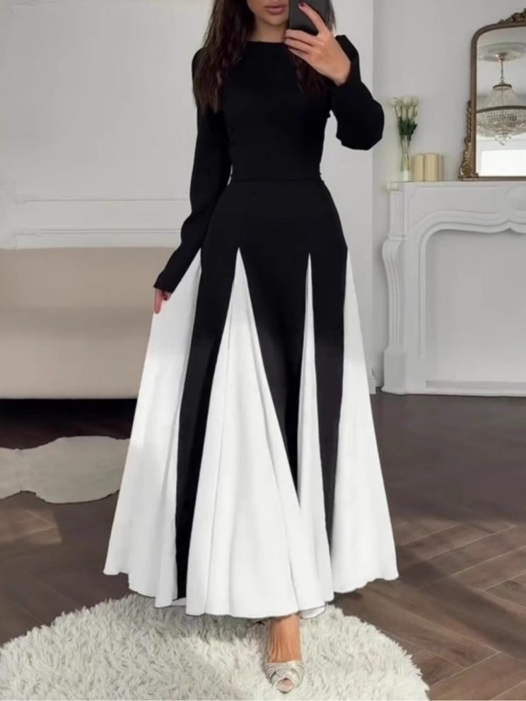 Elegant colorblock dress in black and white with long sleeves, displayed in a chic indoor living room setting.