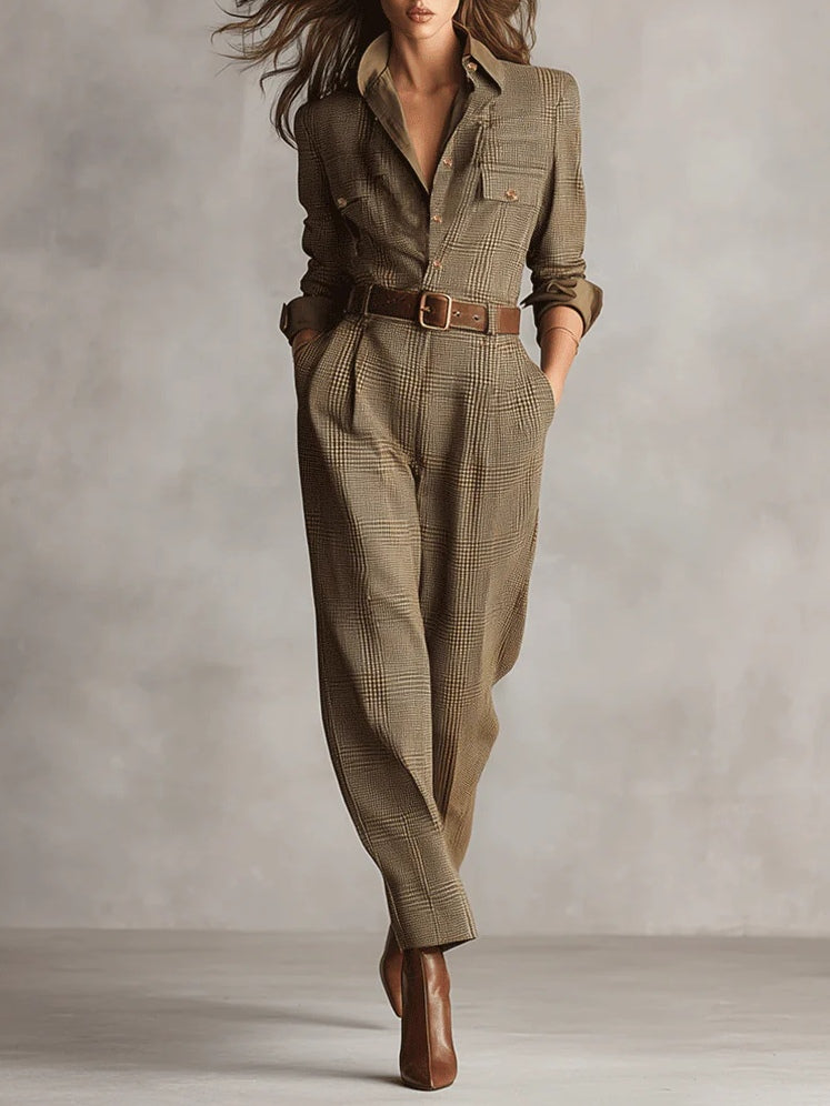 Brown plaid utility jumpsuit with belt, long sleeves, and pockets, styled with ankle boots in a studio setting.