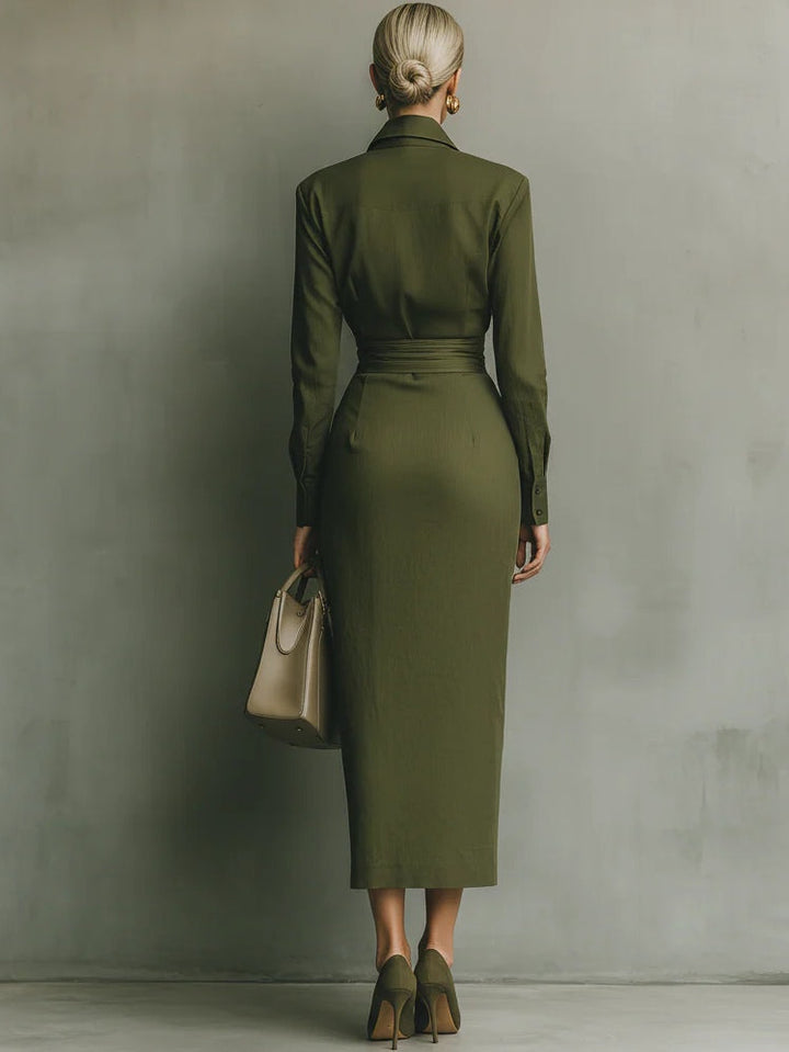 Back view of a woman in an olive green wrap maxi dress, carrying a taupe handbag, in a studio setting.