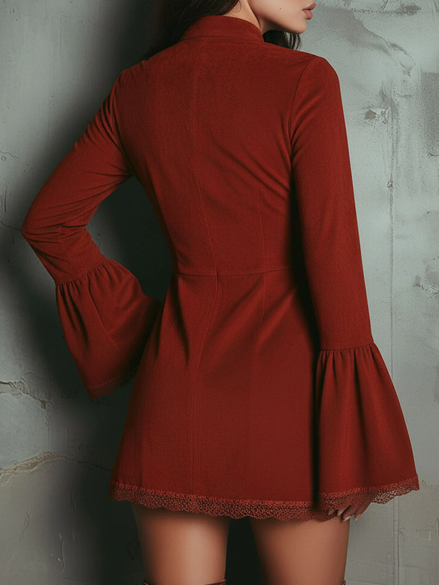 Back view of a red mini dress with flared sleeves and intricate embroidery, worn by a model against a textured wall.
