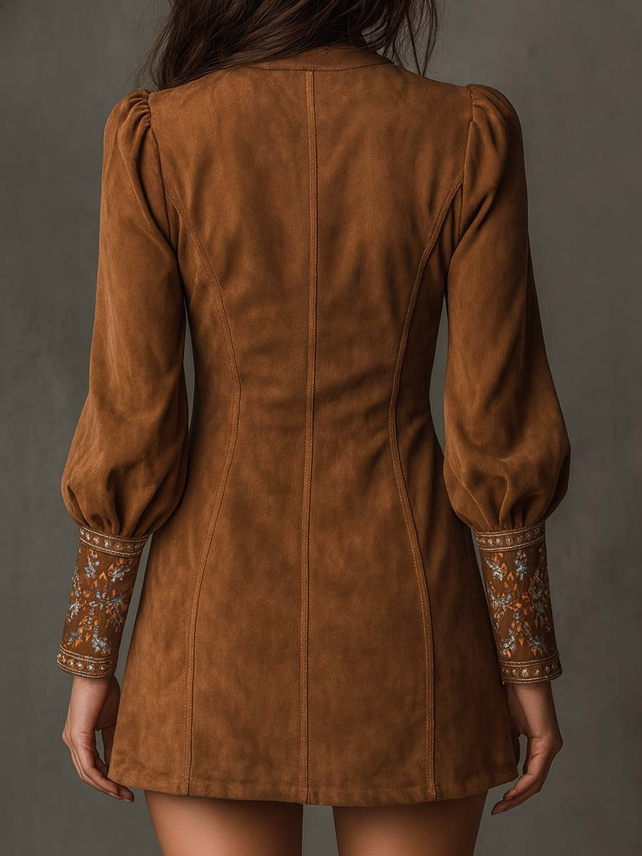 Back view of brown suede mini dress showing puffed sleeves with embroidered cuffs, set against a gray studio background.