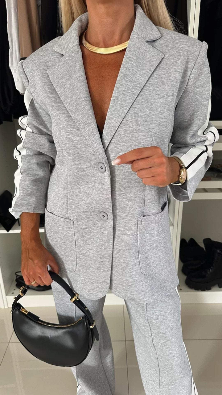 Close-up of grey casual office suit with striped sleeves, shown in a closet with organized footwear.