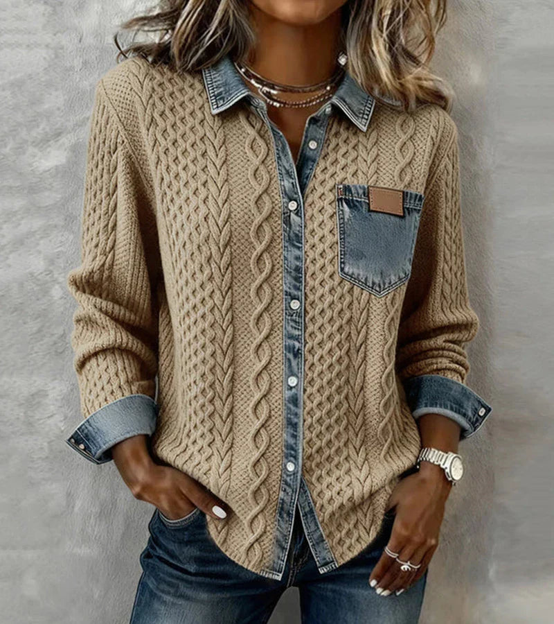 Person wearing a tan knit top with denim details, posed against a textured gray background.