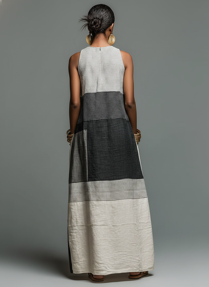 Back view of a sleeveless maxi dress featuring black, gray, and cream color blocks, accessorized with large earrings against a gray backdrop.