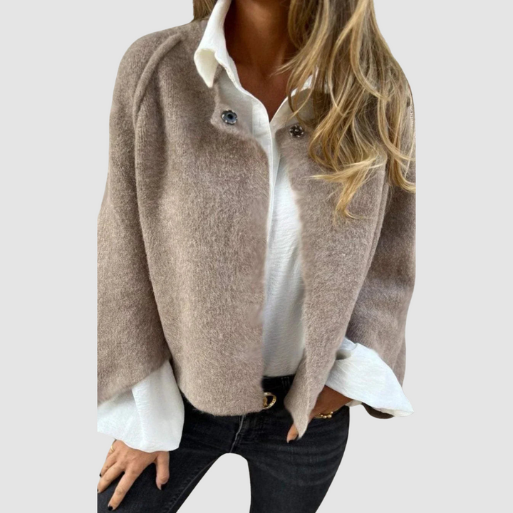 Soft, light brown spring coat over a white shirt on a person, worn with black jeans, studio background.