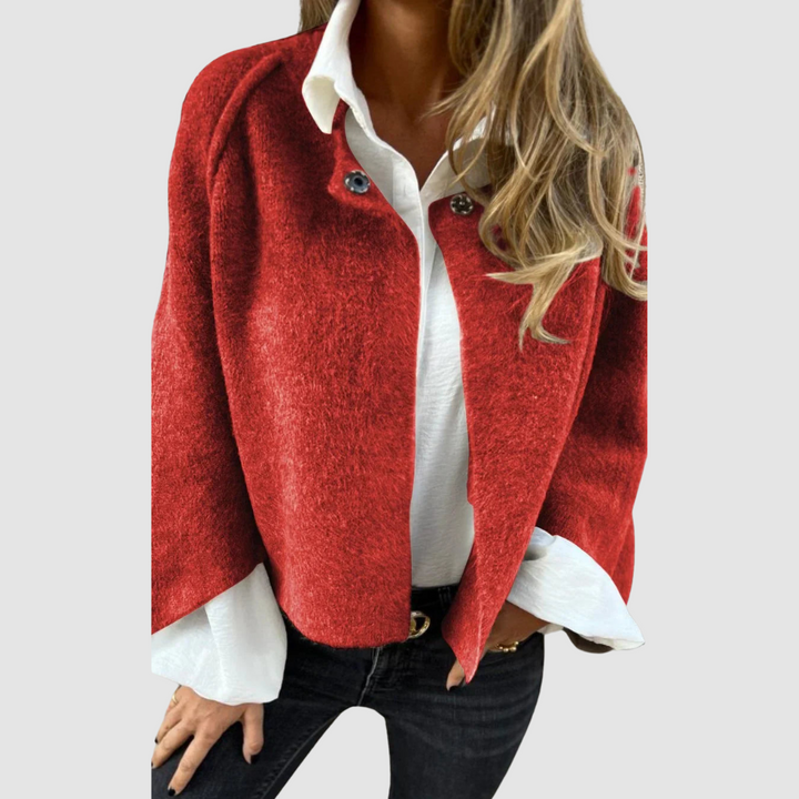 Soft, deep red spring coat over a white shirt on a person, worn with black jeans, studio background.