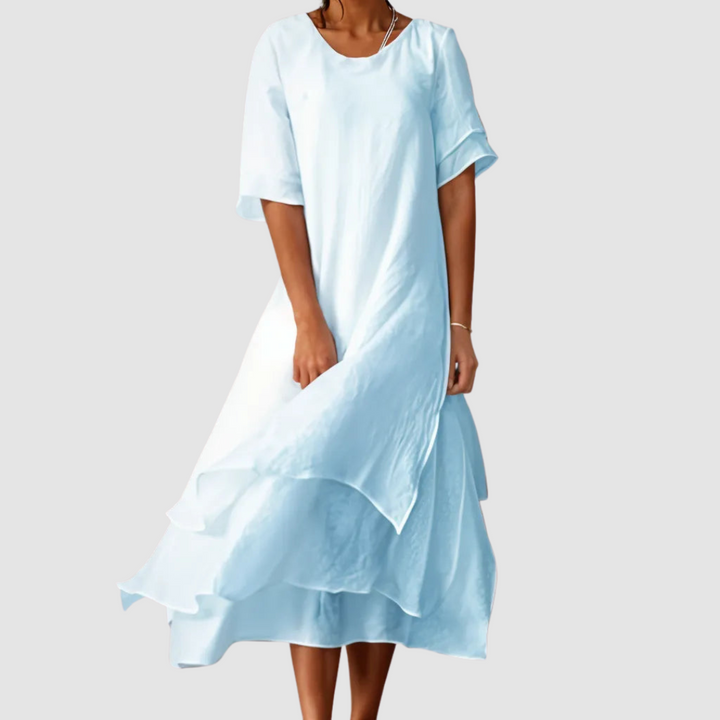 Light blue loose dress with graceful layered design, featured by a model against a gray backdrop.