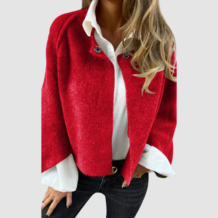 Soft, vibrant red spring coat over a white shirt on a person, worn with black jeans, studio background.