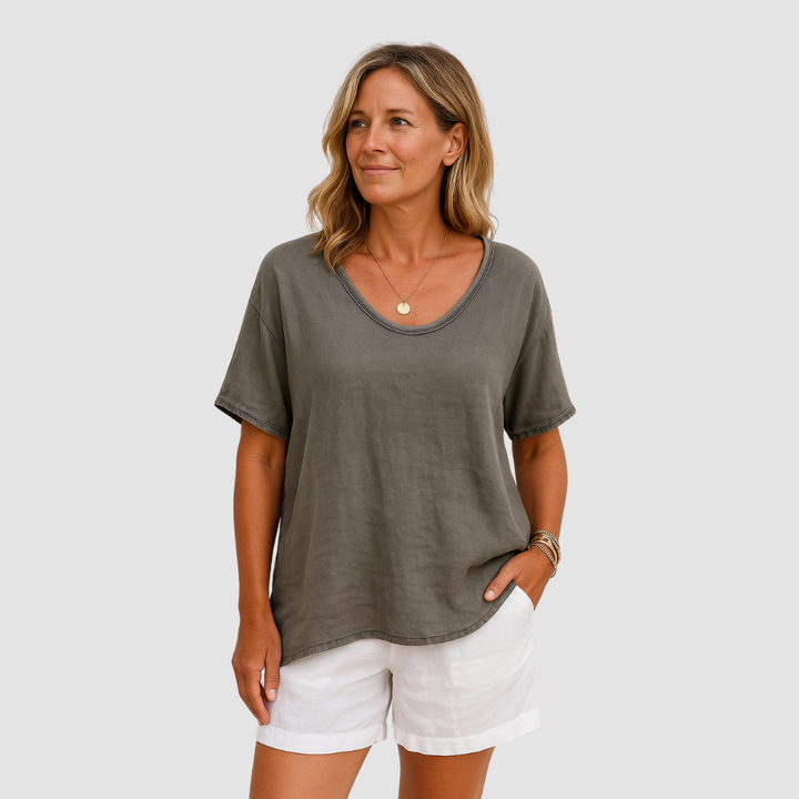 Woman wearing a loose fit green t-shirt, styled with white shorts in a studio setting.
